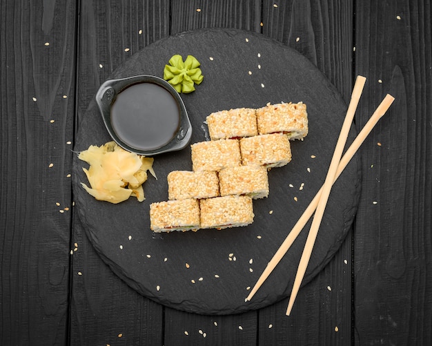 Rollos de sushi en sésamo con aguacate, salmón y queso crema en un negro