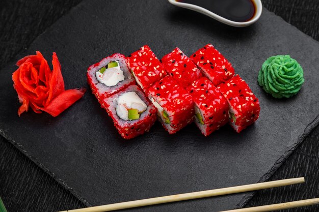 Rollos de sushi sobre un fondo oscuro decorado con hojas de bambú y palillos