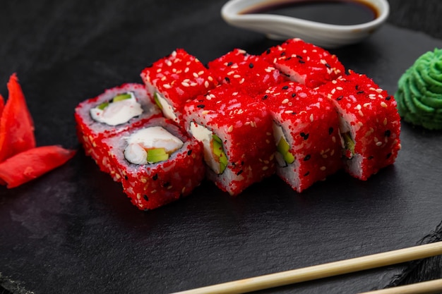 Rollos de sushi sobre un fondo oscuro decorado con hojas de bambú y palillos