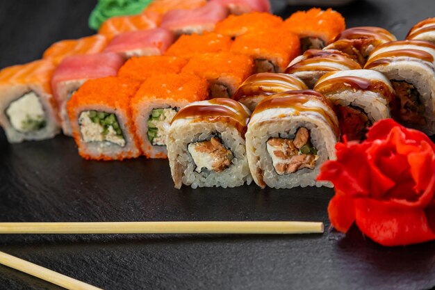 Rollos de sushi sobre un fondo oscuro decorado con hojas de bambú y palillos