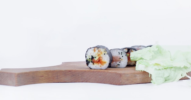 Rollos de sushi en un tablero de corte aislado en blanco