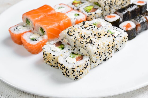 Rollos de sushi tradicionales y maki con aguacate de sésamo y pescado Comida japonesa Vista superior Sobre un fondo blanco