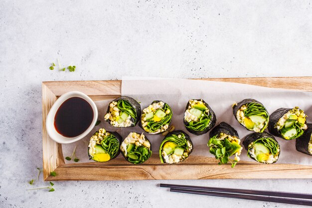 Rollos de sushi verdes del vegano en un tablero de madera.