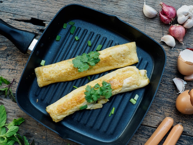 Rollos de tortilla de huevos con salchicha sobre fondo de madera