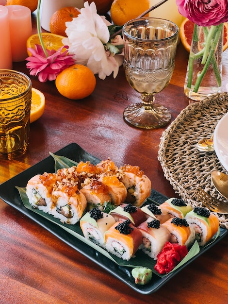 Los rollos de uramaki yacen sobre una hoja de bambú en un plato rectangular sobre la mesa