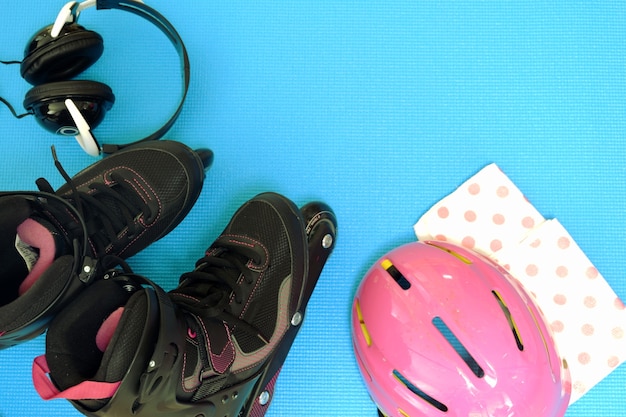 Rollschuhe mit rosa Helm, schwarzes Haupttelefon auf Rückseite des Blaus zurück für Raum