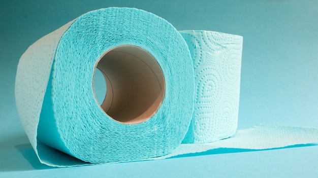 Rolo azul de papel higiênico moderno em um fundo azul. Um produto de papel em uma luva de papelão, usado para fins sanitários a partir de celulose com recortes para facilitar o rasgo. Desenho em relevo.