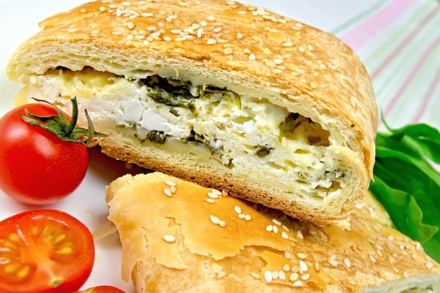 Rolo com camadas de espinafre e queijo e tomates em um fundo de toalha de mesa de linho