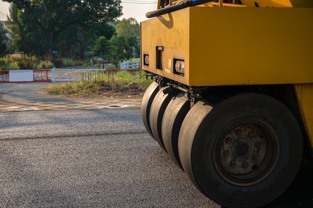 Rolo compactador ou compactador de solo de forte vibração amarela trabalhando em uma estrada de asfalto de mistura quente no canteiro de obras