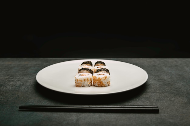 rolo de arroz de sushi japonês salmão e queijo, apresentado em cima do prato branco