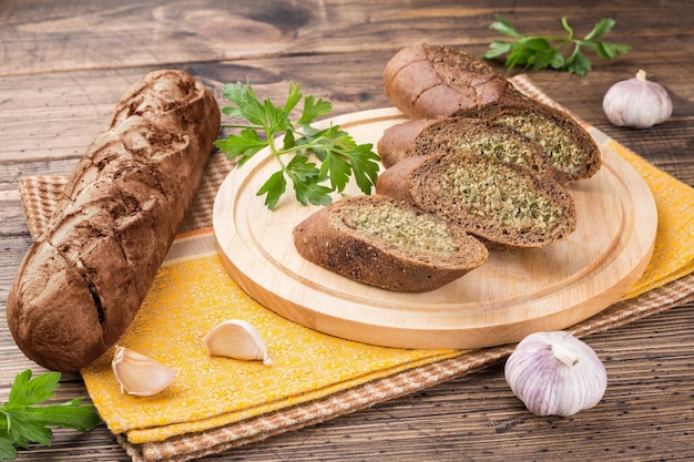 Rolo de baguete de grão de alho em uma tábua de corte de madeira