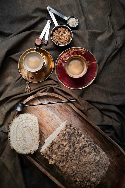 Rolo de biscoito com xícaras de café preto em uma mesa drapeada têxtil