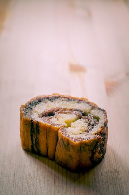 Rolo de bolo de canela na mesa de madeira no café retrô