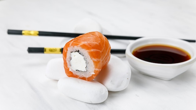 Rolo de cozinha japonesa Filadélfia com salmão em uma mesa branca