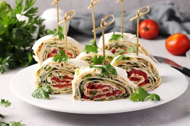 Rolo de lavash com pepinos, tomates, queijo e salsa em fundo cinza. Aperitivo festivo.