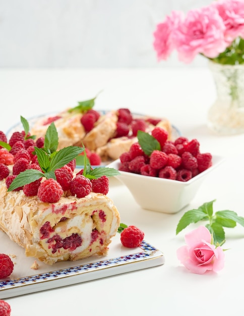 Rolo de merengue assado com creme e framboesa vermelha fresca em um quadro branco