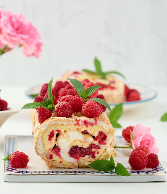 Rolo de merengue assado com creme e framboesa vermelha fresca em uma placa de madeira preta