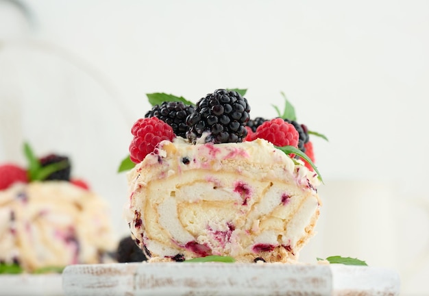 Rolo de merengue assado com creme e frutas frescas em uma deliciosa sobremesa de tábua de madeira branca