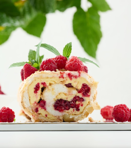 Rolo de merengue assado com creme e fundo branco de framboesa vermelha fresca