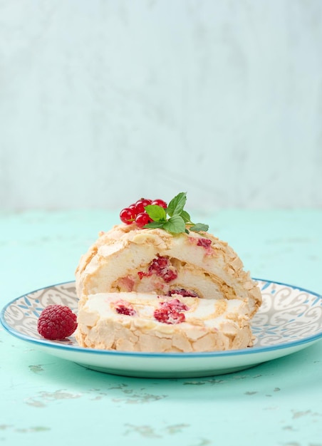 Rolo de merengue assado com frutas vermelhas em um fundo branco de prato redondo