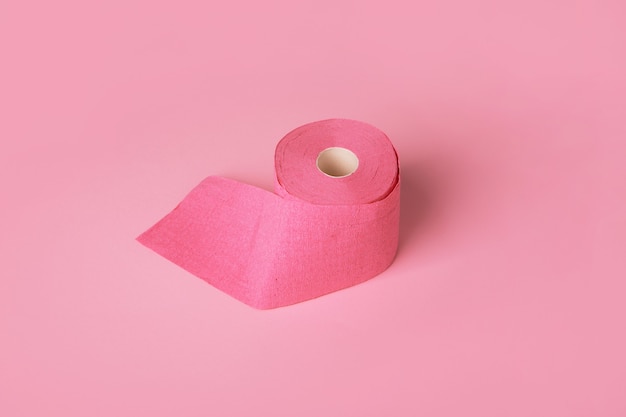 Rolo de papel higiênico sobre fundo rosa, item de higiene pessoal