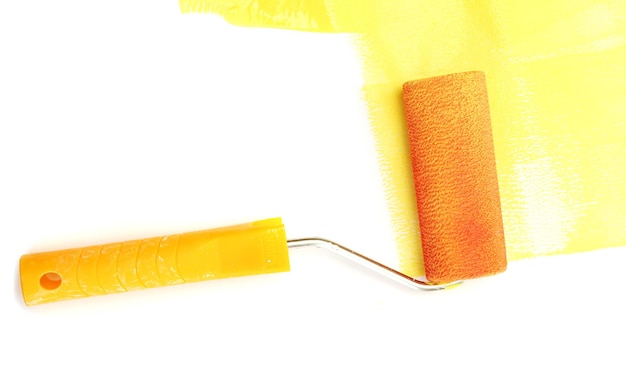 Foto rolo de pintura com tinta amarela isolada em branco