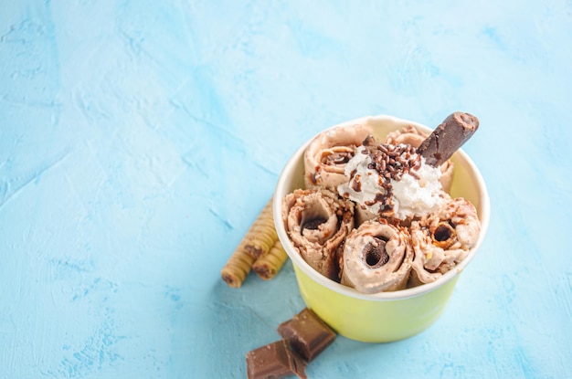 Rolo de sorvete de chocolate e café, com pedaços de chocolate e biscoitos em fundo azul