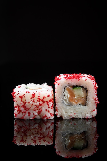 Rolo de sushi Califórnia com pepino de salmão e queijo creme em fundo preto com reflexão