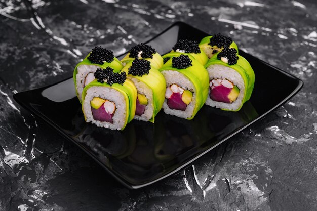 Foto rolo de sushi coberto de abacate com atum e caviar preto