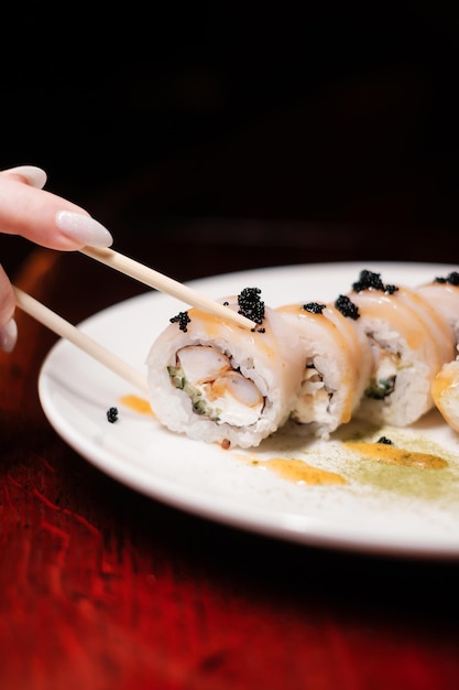 Rolo de sushi em chapa branca com pauzinhos e caviar