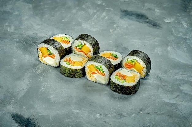 Rolo de sushi Futomaki com omelete de salmão e pepino em fundo cinza Ruído adicionado na pós-produção