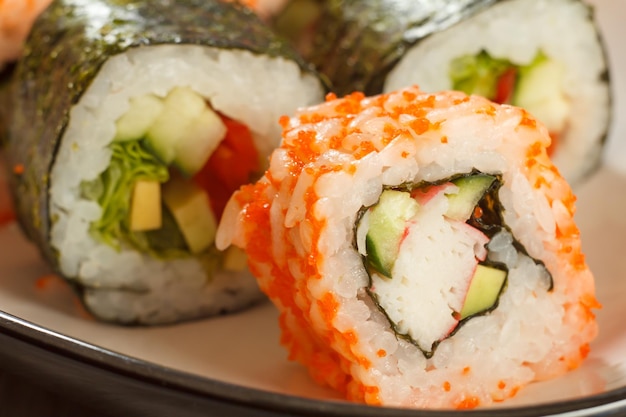 Rolo de sushi Uramaki California com pedaços de arroz nori de pedaços de caranguejo abacate e pepino