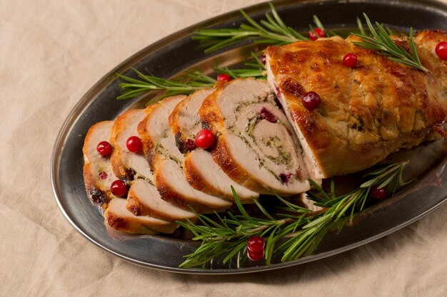 Foto rolo de navidad de filete de pavo relleno de hongos y queso con arándanos y romero