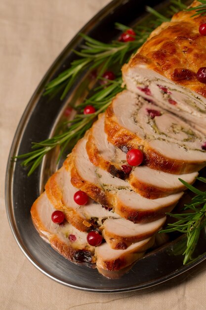 Foto rolo de navidad de filete de pavo relleno de hongos y queso con arándanos y romero