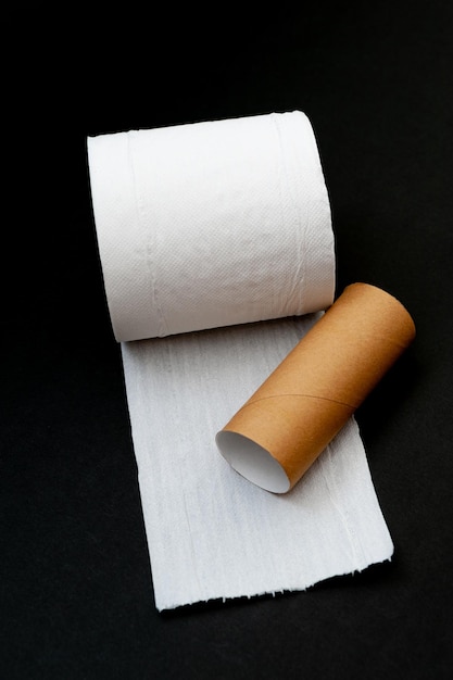Foto rolo único de papel higiênico branco desenrolado e tubo de núcleo de papel isolado em fundo preto