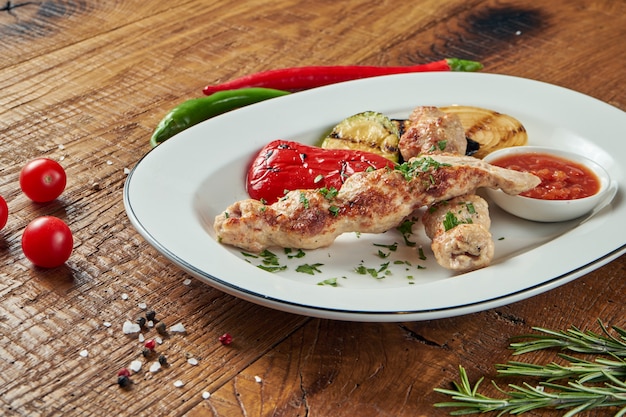 Rolos apetitosos de kebab de Lyulya - cozidos a partir de carne picada de frango em chapa branca com legumes grelhados. mesa de madeira