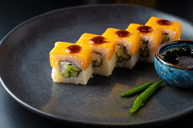 Rolos asiáticos tradicionais e sushi com molho de soja e wasabi servidos em fundo escuro