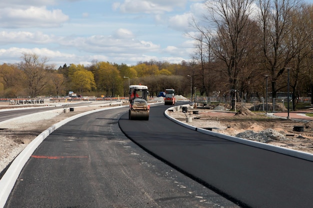 Rolos de asfalto pavimentando novo asfalto dirigindo em linha um perto do outro Nova construção de estradas Foco seletivo