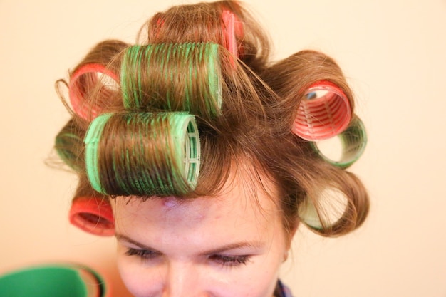 Rolos de cabelo na cabeça da mulher. Fazendo um penteado elegante em casa.