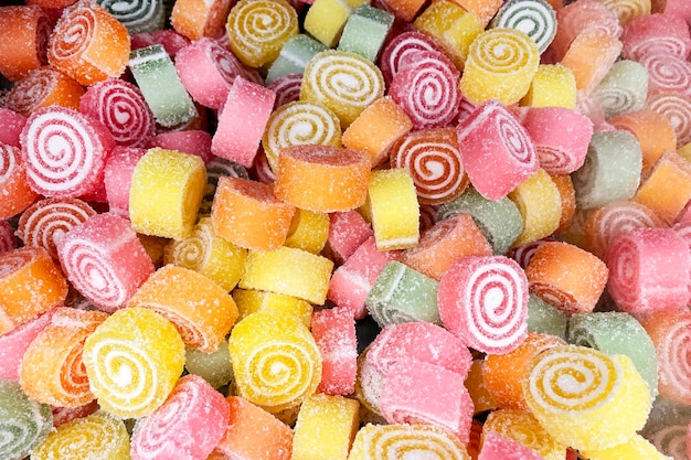 Rolos de doces de geléia multicoloridos misturam-se com textura de açúcar granulado branco