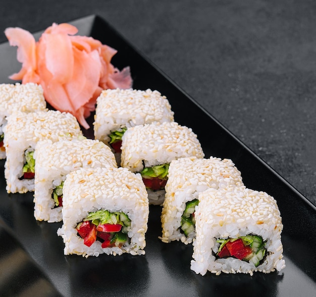 Rolos de maki de sushi vegetariano com sementes de gergelim na chapa preta