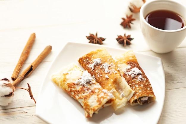 Rolos de panquecas saborosos e xícara de chá e em mesa de madeira Vista superior Conceito de quarentena