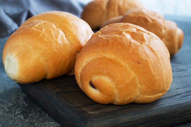 Rolos de pão de trigo fresco. Rolos para cachorro-quente ou hambúrguer. Espaço de cópia de fundo escuro.