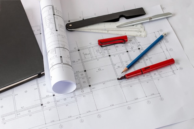 Rolos de projetos de arquitetura e plantas de casas sobre a mesa e ferramentas de desenho do arquiteto.