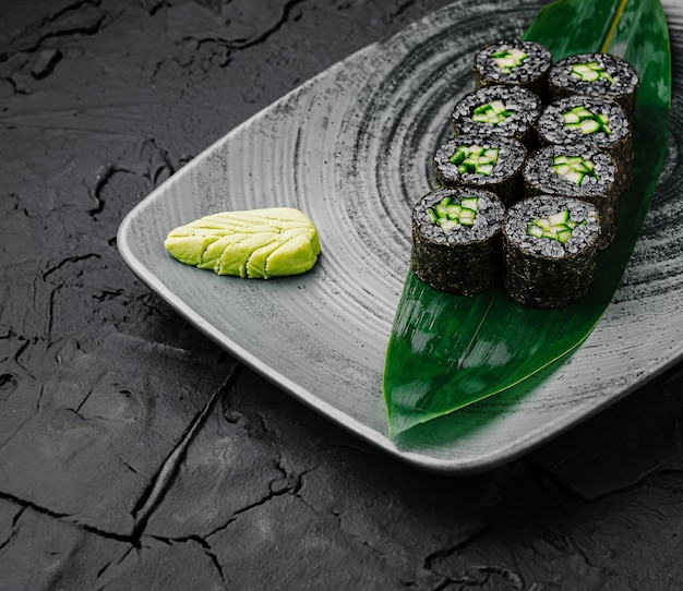 Rolos de sushi arranjados elegantemente em um prato preto com textura