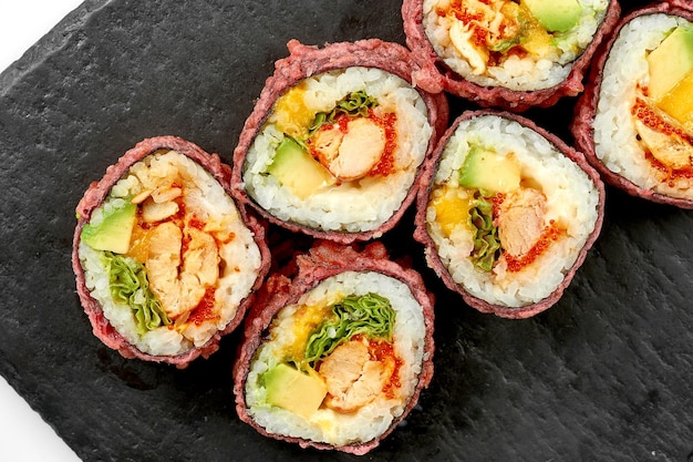 Rolos de sushi com camarão e abacate em um prato sobre fundo branco Closeup foco seletivo