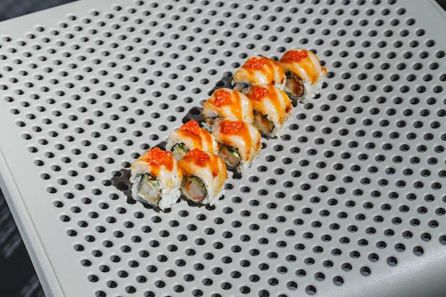 Rolos de sushi com pepino de camarão enguia e queijo creme decorado com caviar vermelho