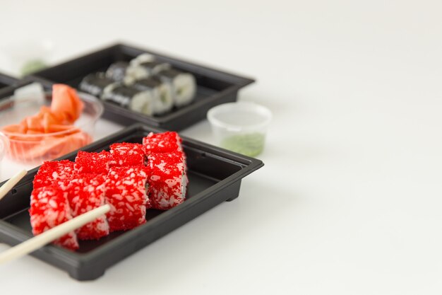 Rolos de sushi com salmão e gengibre em uma mesa de madeira branca, copyspace.