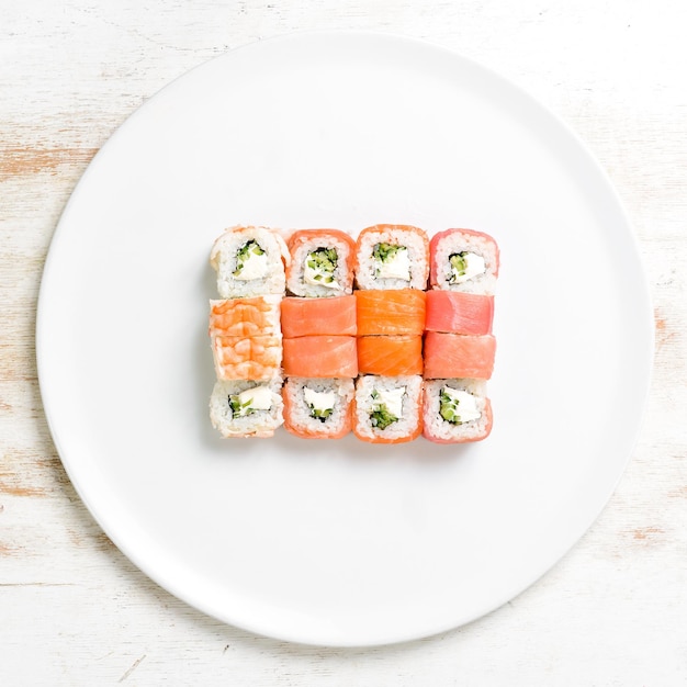 Rolos de sushi com salmão em um prato branco Vista superior em um fundo branco