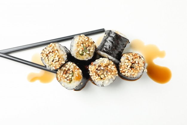 Rolos de sushi delicioso, soja e pauzinhos na superfície branca